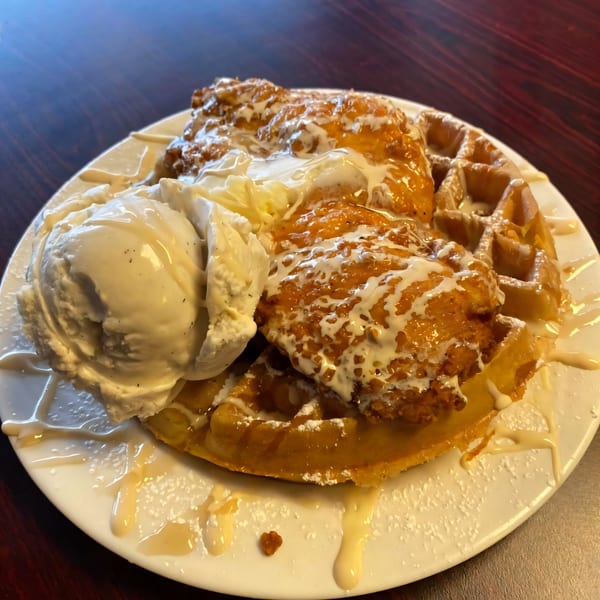 B-UNOS chicken and waffles with vanilla ice cream, drizzled with white sauce and powdered sugar.