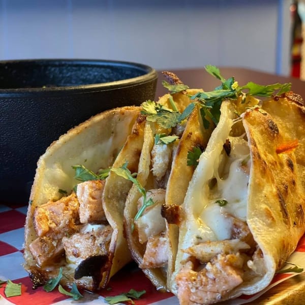 Three B-UNOS tacos filled with chicken and melted cheese, garnished with fresh cilantro.