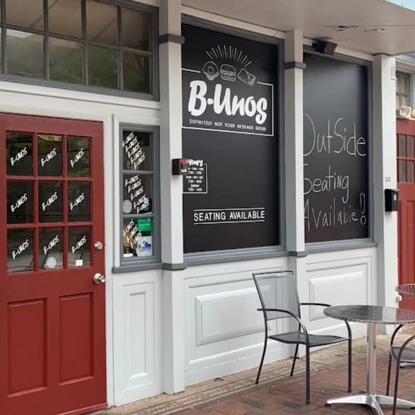 The B-UNOS restaurant exterior with a red door, black windows, and outdoor seating.